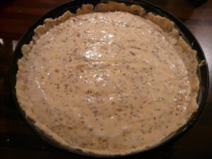 Torta salata con pasta bucherellata pronta per la cottura "in bianco" su una teglia da forno.