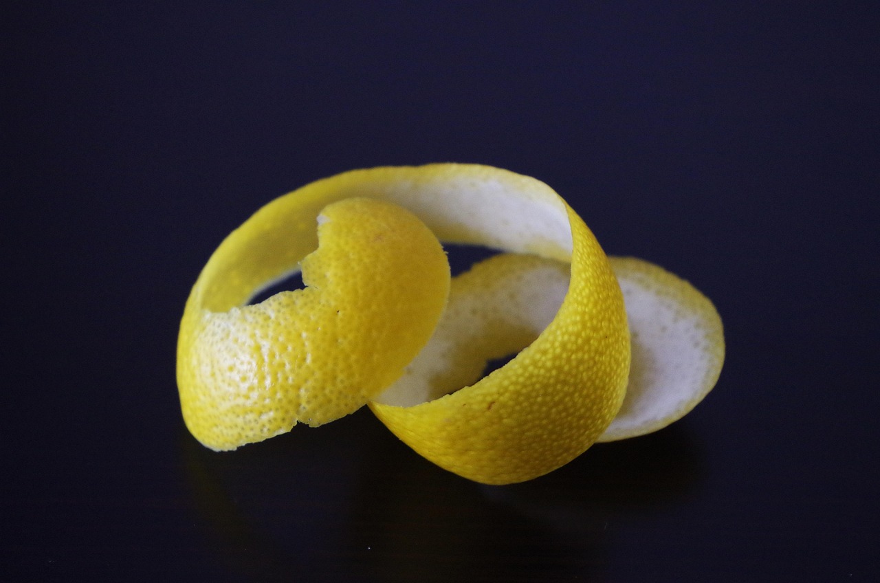 Buccia di limone spremuta posizionata accanto a un bicchiere di limonata e una lavastoviglie.