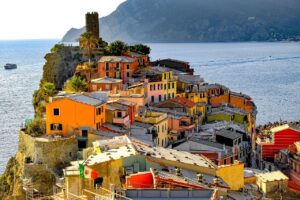 Veduta panoramica delle Cinque Terre con borghi colorati a picco sul mare, ideale per visitare senza spendere troppo.